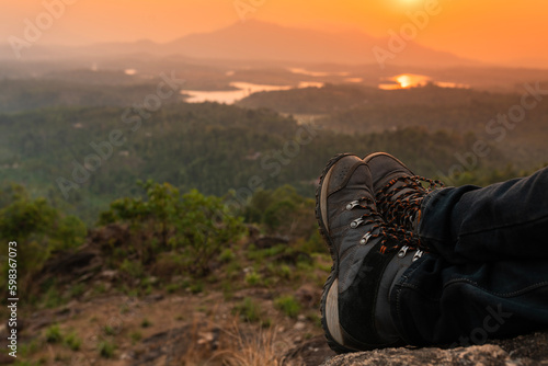 Tourist relaxing on the mountain during sunset, trekking shoes with beautiful nature view