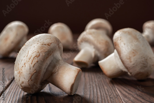 Fresh champignon mushrooms on wooden table, closeup.