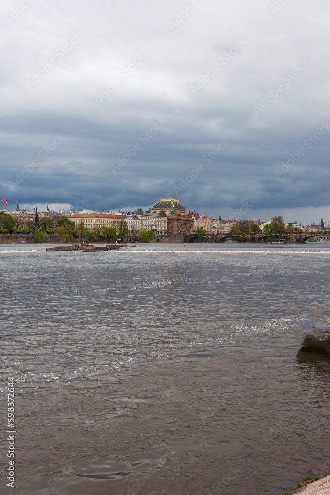 Fototapeta premium HDR of Vltava Moldau river in Prague with dark sky. The river passes in the middle of the city center, the sky is dark threatening, cruise ships for tourists roam the river.