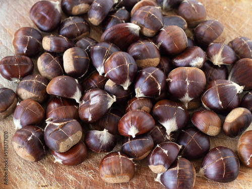 Closeup of brown chestnuts with cut on top of a wooden table. Top view. Healthy organic autumn food.
