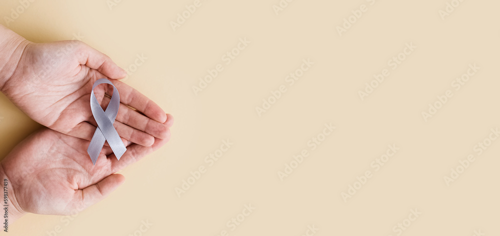 World Brain Tumor day. Person's hands are holding a gray ribbon. This is observed every year on June 8th. World Brain Tumor day. Person's hands are holding a gray ribbon. This is observed every year on June 8th.