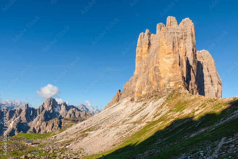 View on Tre Cime di Lavaredo with shelter in Dolomites mountains at sunrise. Three famous mountain peaks
