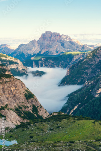 Fototapeta Naklejka Na Ścianę i Meble -  Mountain canyon filled with clouds at sunrise in Dolomites, Alps, Italy. Vertical orientation. Italian mountain landscape