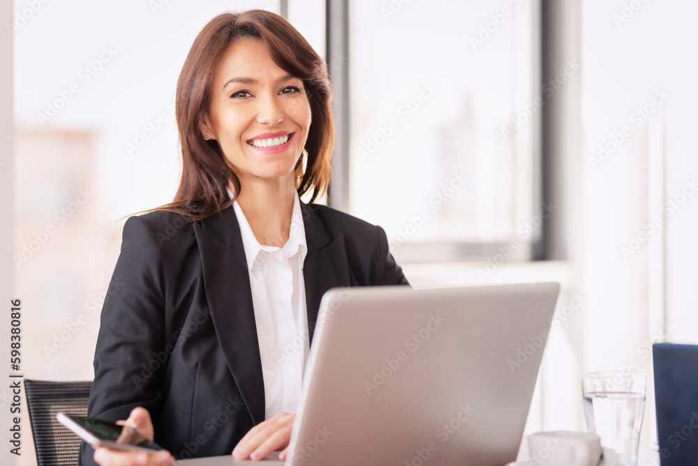 Executive mid aged business woman sitting in a modern office and working Executive mid aged business woman sitting in a modern office and working
