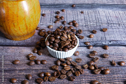 profumati grani di caffè su piano di legno con piccola tazzina bianca