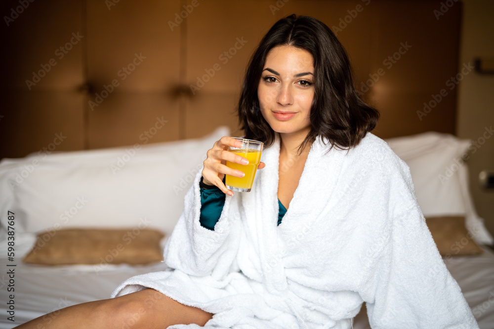 Portrait of beautiful woman in white bathrobe drinking orange juice Portrait of beautiful woman in white bathrobe drinking orange juice