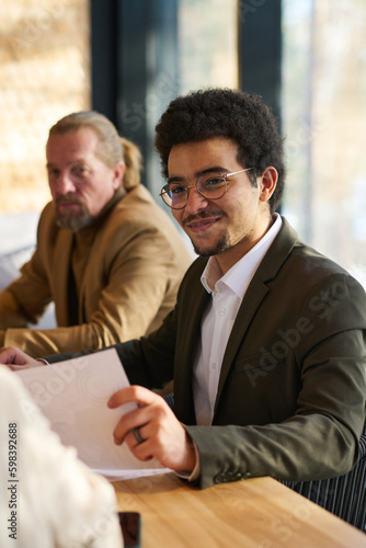 Obraz na plátne Smiling male broker or economist with financial document in hand sitting in fron