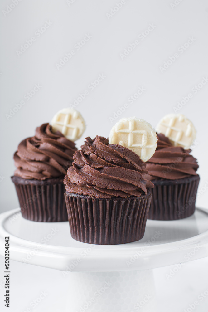 Chocolate cupcake with dark chocolate buttercream, double chocolate cupcakes with american buttercream, tall swirl frosting on a cupcake with a wafer Chocolate cupcake with dark chocolate buttercream, double chocolate cupcakes with american buttercream, tall swirl frosting on a cupcake with a wafer
