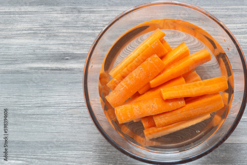 Canvas Print Sliced carrots soaking in a glass bowl of water
