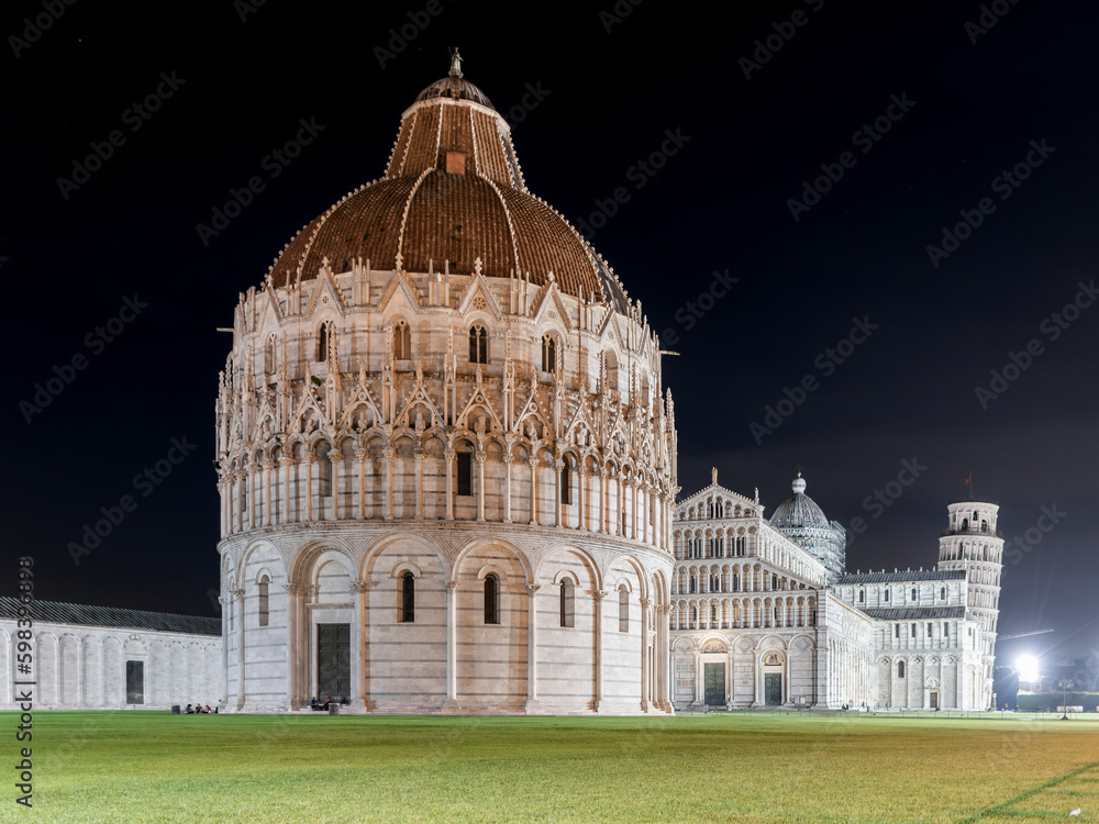 Night view of the Piazza dei Miracoli with the famous buildings baptistery of St. John, the cathedral, and the leaning tower in the background. Tuscany, Italy.