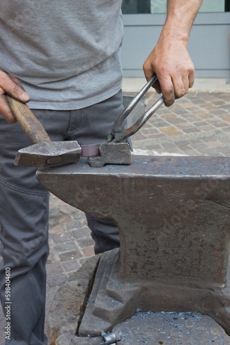 Lavorazione del ferro a caldo con incudine e martello e pinza con operaio