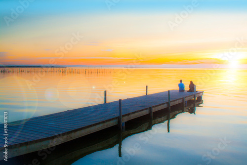 pareja de enamorados mirando el atardecer en el embarcadero del lago 