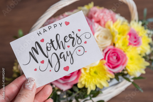 hand with mothers day greeting card - Beautiful blooming flowers in basket.Creative bouquet with chrysanthemums, roses, carnations.floral present