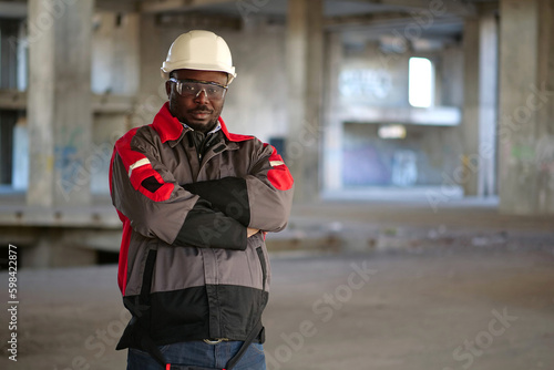 Photos African american worker stands at construction area and looks at camera