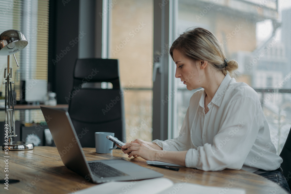 Young woman supervisor works in the office in her office behind a laptop. Young woman supervisor works in the office in her office behind a laptop.
