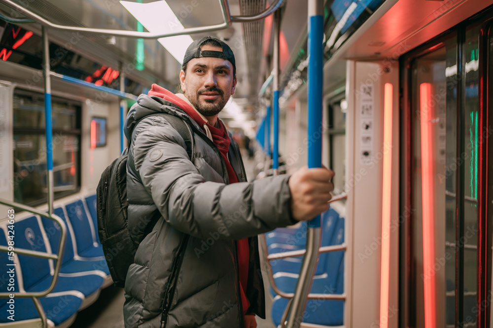 A young man rides standing in a modern subway car. A young man rides standing in a modern subway car.