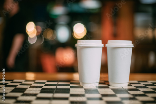 Paper white cups of tea or coffee are taken out on the coffee shop table. No one.