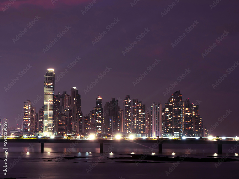 Fototapeta premium Glowing city lights and tall architectural buildings under purple twilight sky