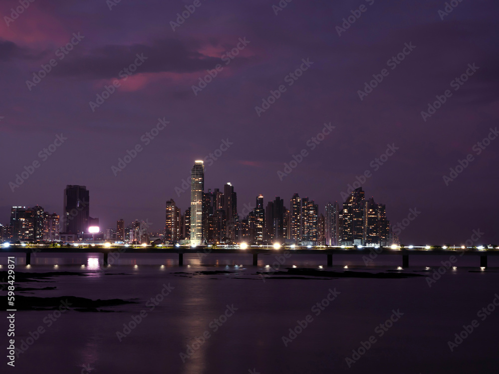 Wonderful purple coloured sky above the illuminated modern city district at dusk