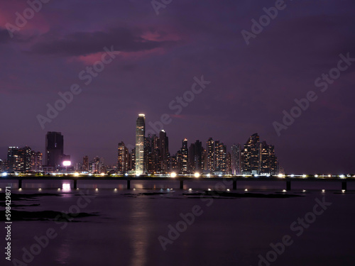 Wonderful purple coloured sky above the illuminated modern city district at dusk