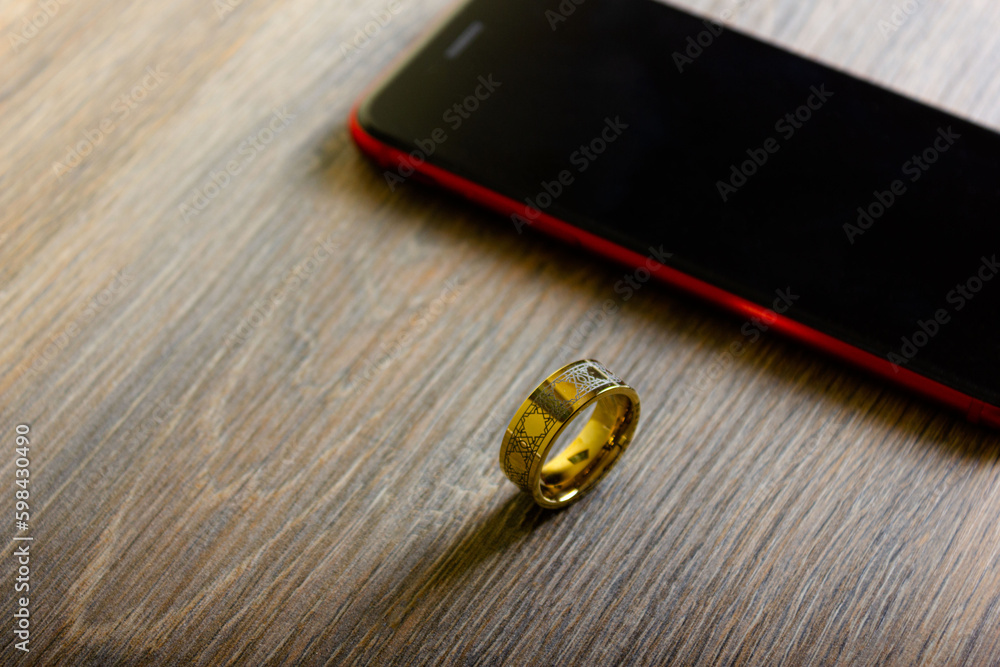 Golden ring and smartphone on wooden table Golden ring and smartphone on wooden table
