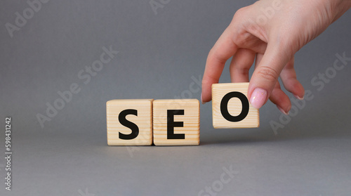 SEO - Search Engine Optimization symbol. Wooden blocks with words SEO. Businessman hand. Beautiful grey background. Business and SEO concept. Copy space.