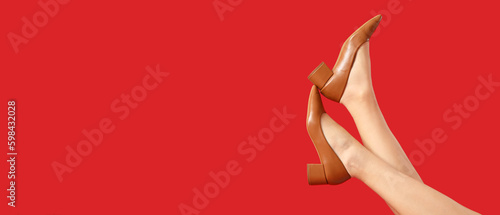 Legs of woman in stylish shoes on red background with space for text