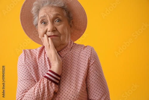 Shocked senior woman on yel...