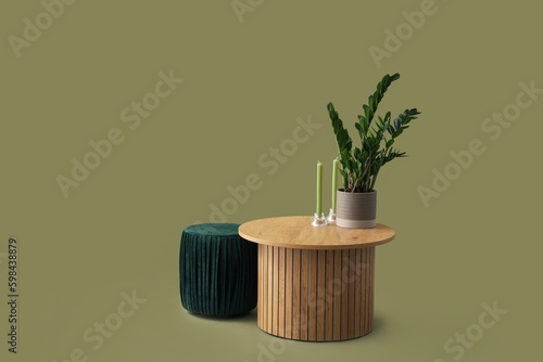 Wooden coffee table with houseplant and aroma candles on green background