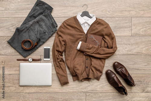 Male clothes with accessories, laptop and mobile phone on wooden floor