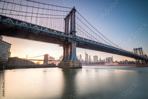 Manhattan Bridge seen from the coast next to the D.U.M.B.O area  during dusk with completely clear skies