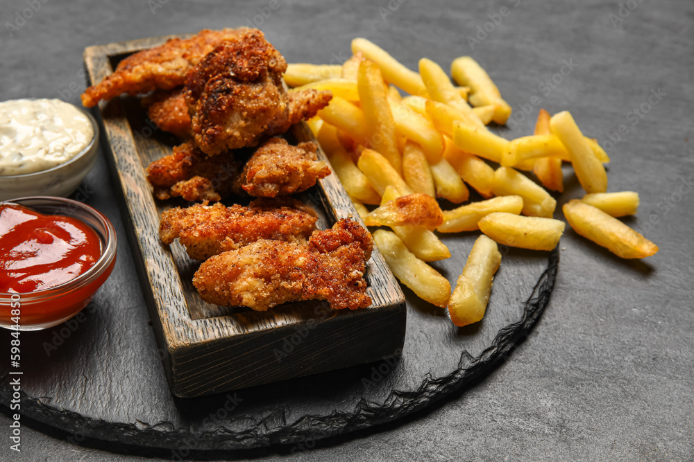 Boards of tasty fried codfish with french fries on dark background, closeup Boards of tasty fried codfish with french fries on dark background, closeup