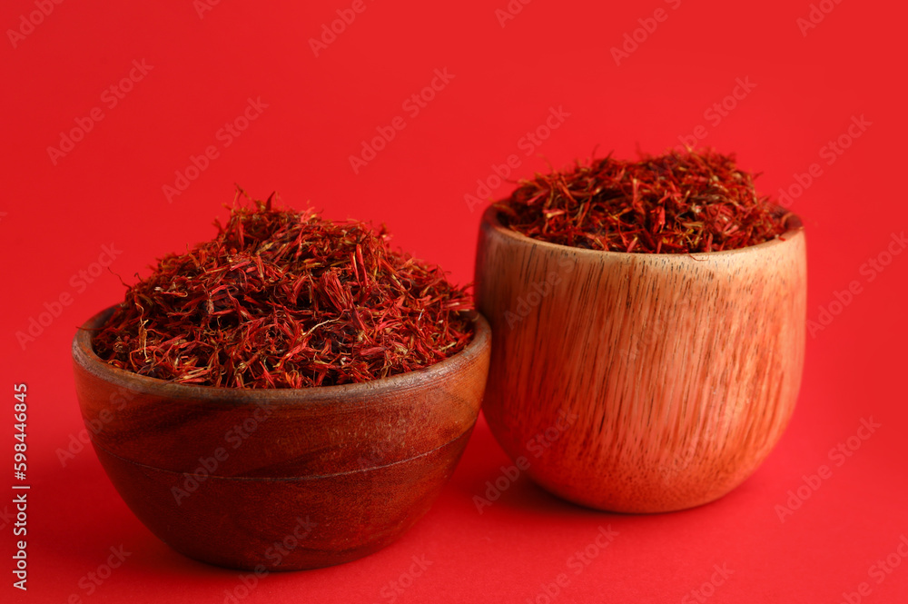 Wooden bowls with pile of saffron on red background Wooden bowls with pile of saffron on red background