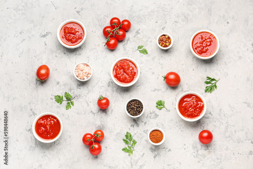 Bowls with tasty tomato sauce and ingredients on grunge background