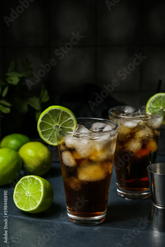 Glasses of cold Cuba Libre cocktail on dark background