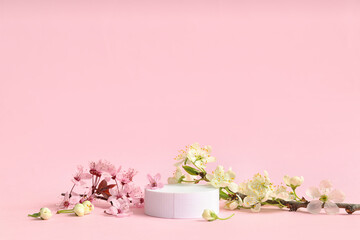 Decorative podium and blooming branches on pink background