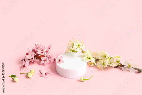 Decorative podium and blooming branches on pink background