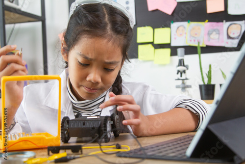 School student making robotic cars. Girl at robotics school makes robot managed from the constructor, child learns robot constructing.