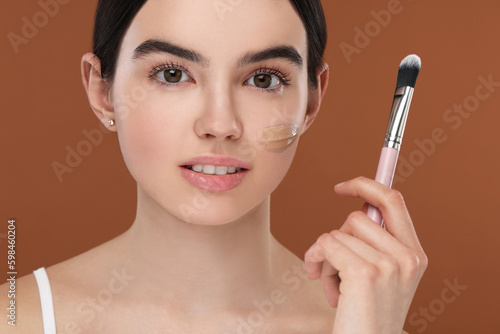 Teenage girl with swatch of foundation and makeup brush on brown background