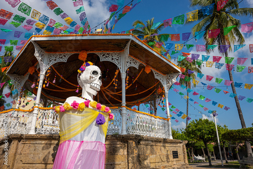 Colonial kiosk in the center of the park in Villa de Alvarez, Colima, Mexico, decorated with a huge catrina, cempasúchil flowers and the traditional papel picado. photo