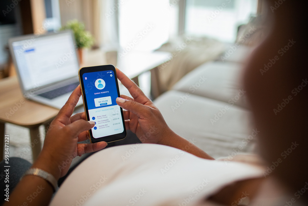 Young pregnant latina woman using a banking app on the couch in the living room Young pregnant latina woman using a banking app on the couch in the living room