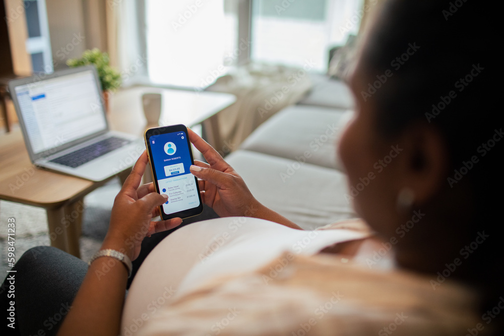 Young pregnant latina woman using a banking app on the couch in the living room Young pregnant latina woman using a banking app on the couch in the living room