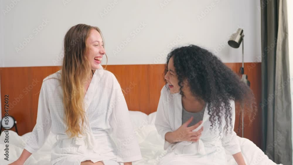 Two young beautiful woman have fun talking together in bedroom at home. Two young beautiful woman have fun talking together in bedroom at home.