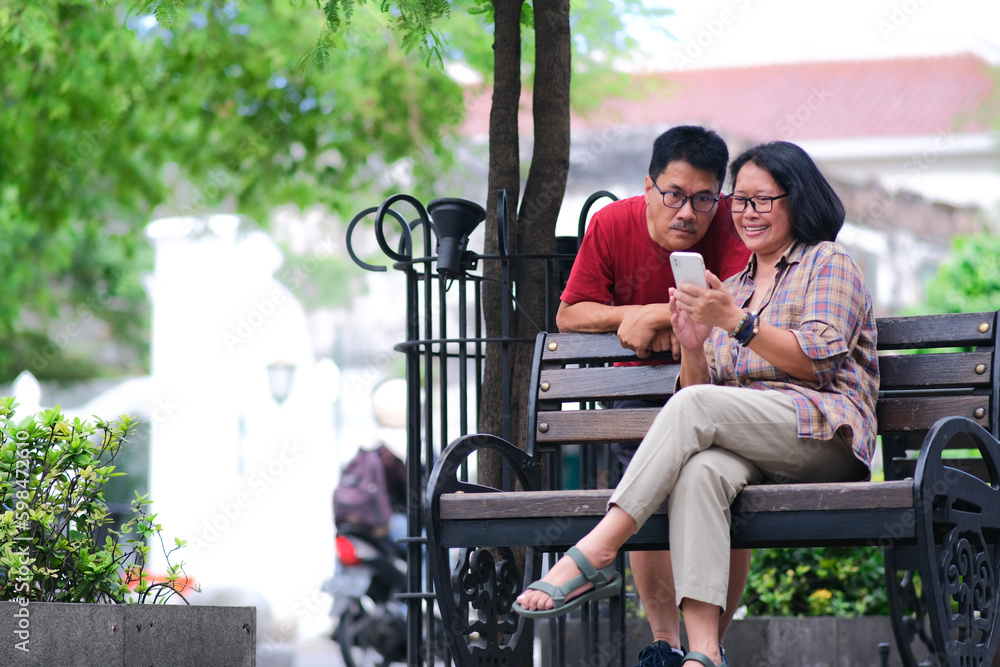 Couple of man and woman sitting on a park bench looking at their ...