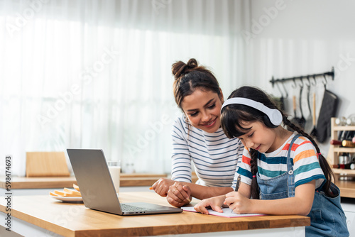Fototapeta Caucasian young girl kid learning online class at home with mother
