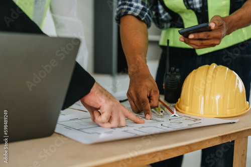 multi ethnic engineer brainstorming and measuring for cost estimating on paperworks and floor plan drawings about design architectural and engineering for houses and buildings