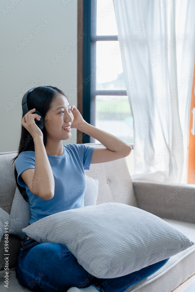 Peaceful girl in modern wireless headphones sit relax on comfortable couch listening to music, on cozy sofa, stress free concept. Peaceful girl in modern wireless headphones sit relax on comfortable couch listening to music, on cozy sofa, stress free concept.