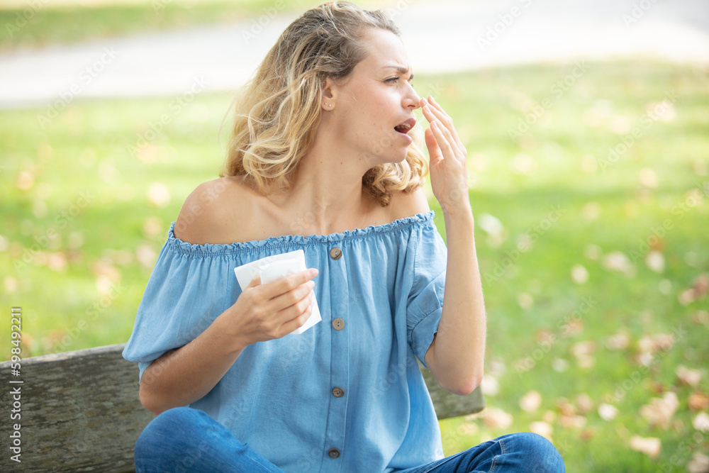 Fototapeta premium beautiful woman using tissue while sneezing in park