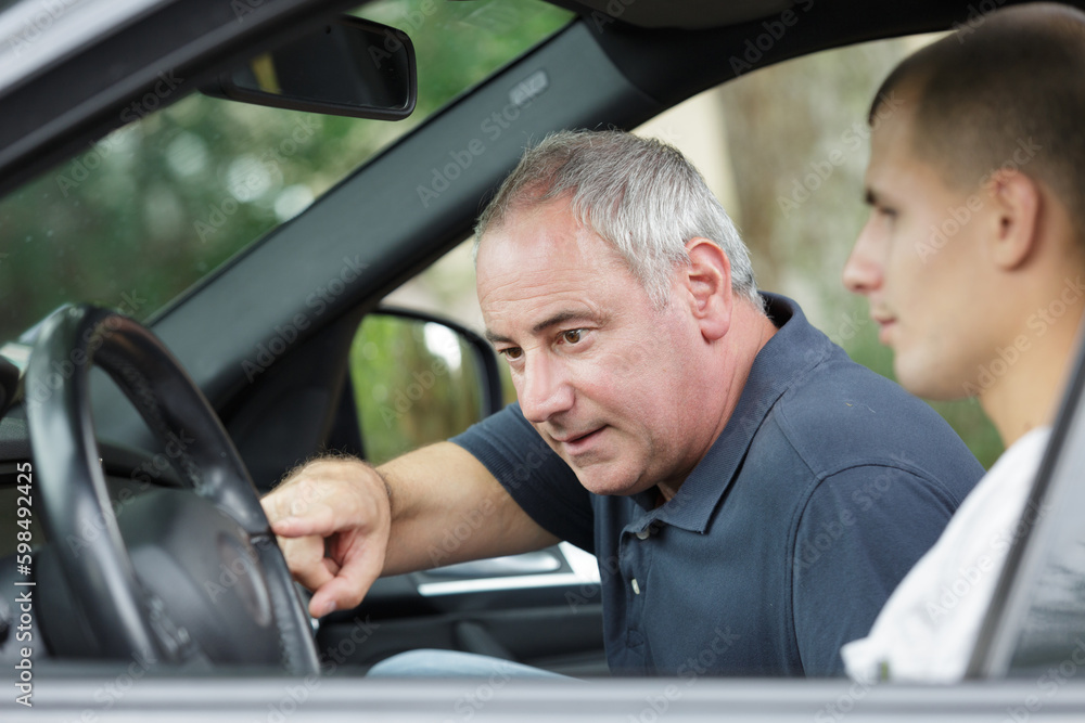 driving teacher showing function buttons to student driving teacher showing function buttons to student