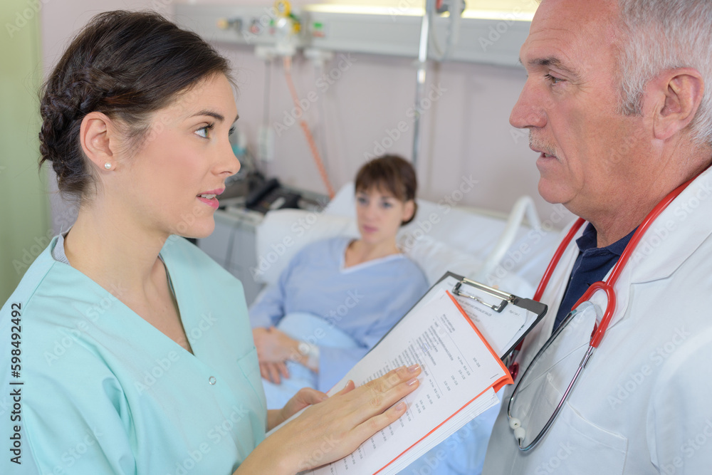 nurse talking to male doctor in hospital patients room nurse talking to male doctor in hospital patients room